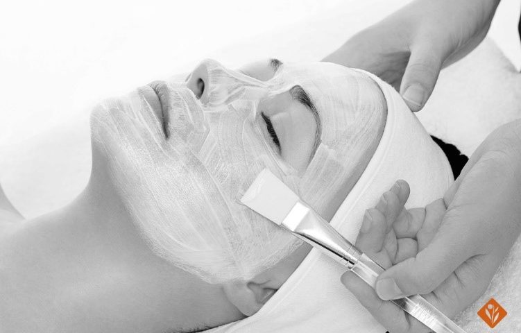 Black and white, woman getting a facial done with a brush