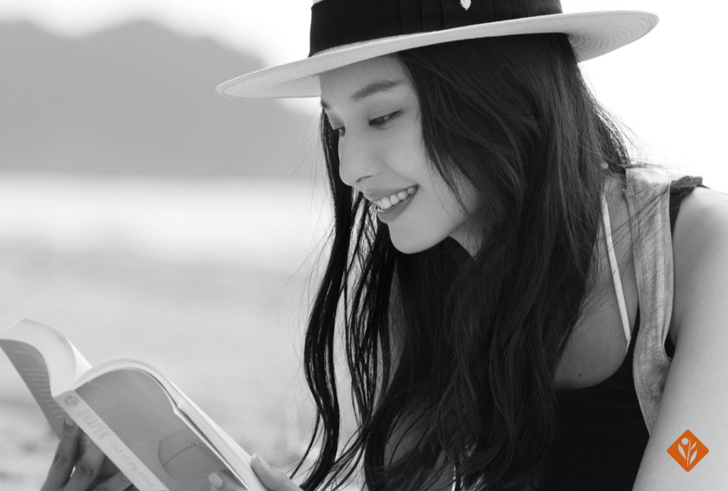 Black and white image of woman in a sun hat reading a book