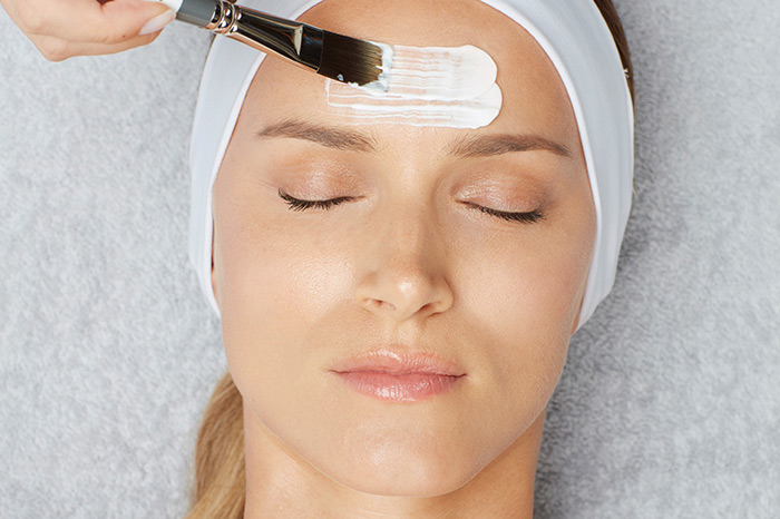 Woman receiving a facial using a brush on her forehead