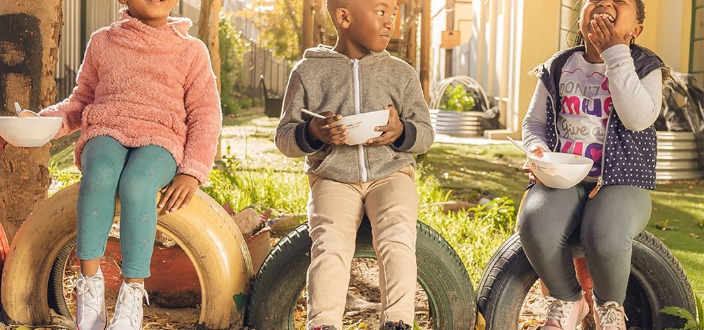 Three children smiling and having breakfast