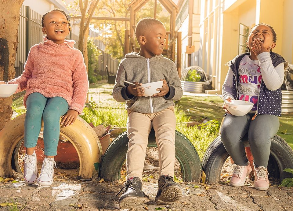 Three children smiling and having breakfast