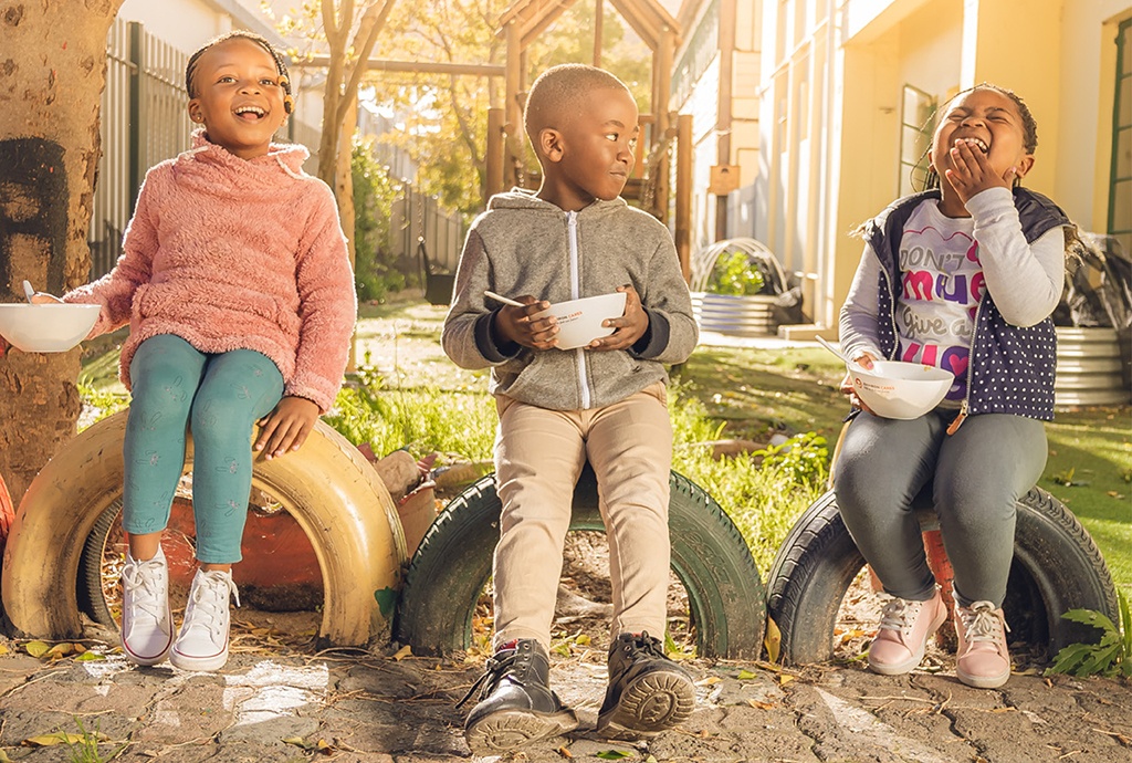 Three children smiling and having breakfast