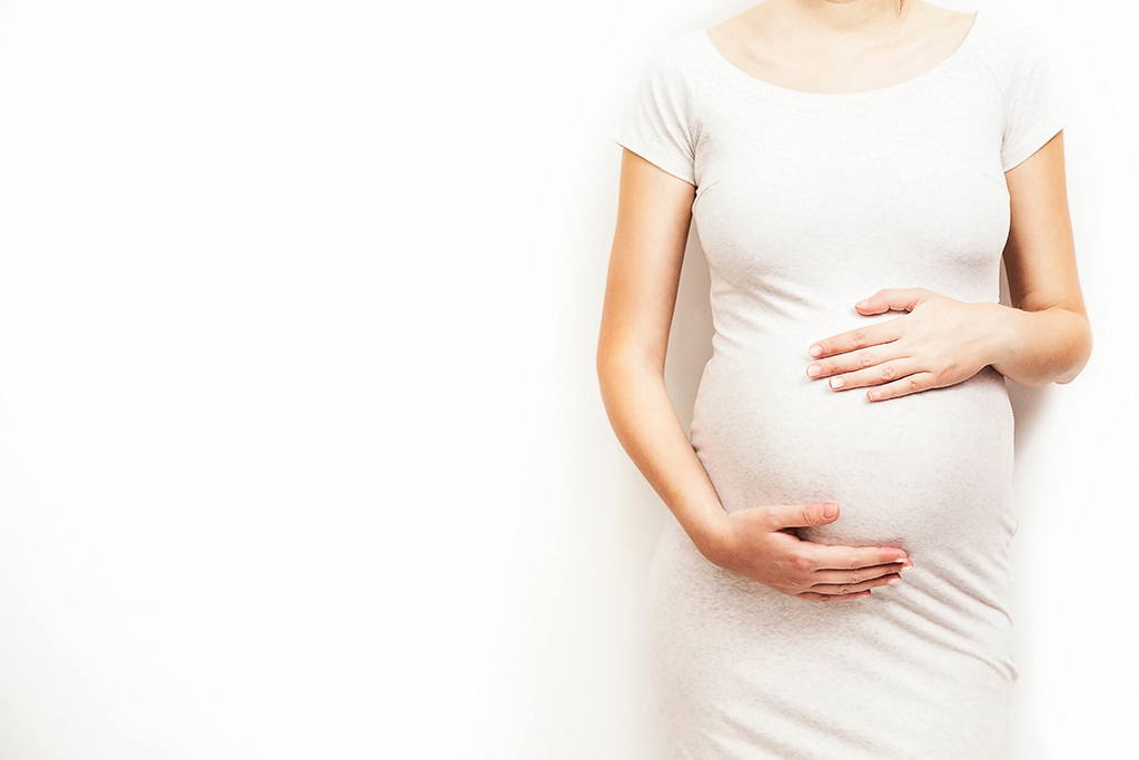 Pregnant woman holding belly with both hands