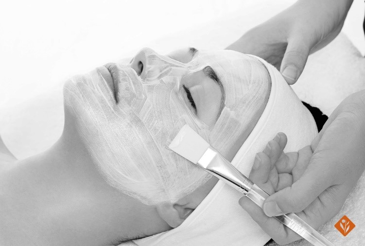 Black and white, woman getting a facial treatment with a brush