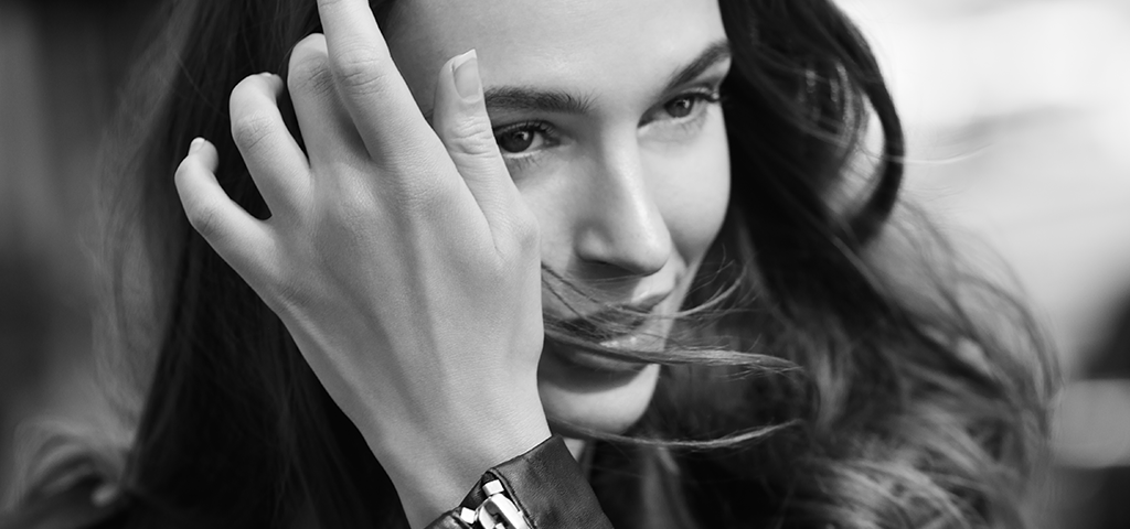 Image of a woman in a leather jacket moving her hair away from her face