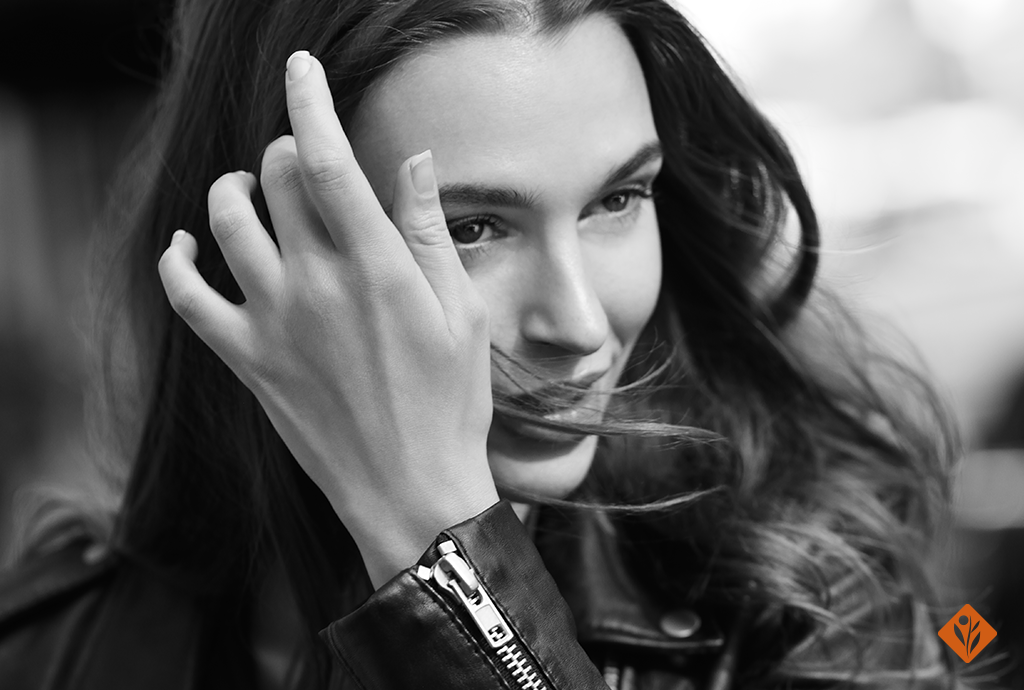 Image of a woman in a leather jacket moving her hair away from her face
