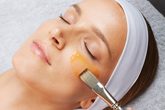 Woman getting under eye treatment with a serum and brush